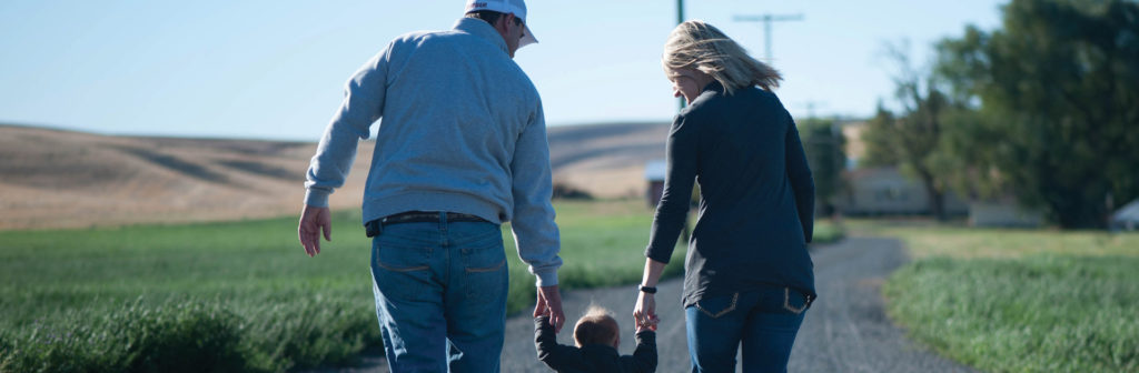 Two people walking in rural setting with a child in between them