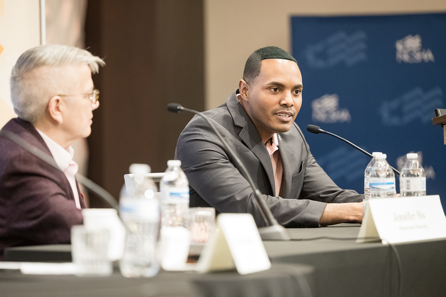 Two speakers at a conference table with microphones