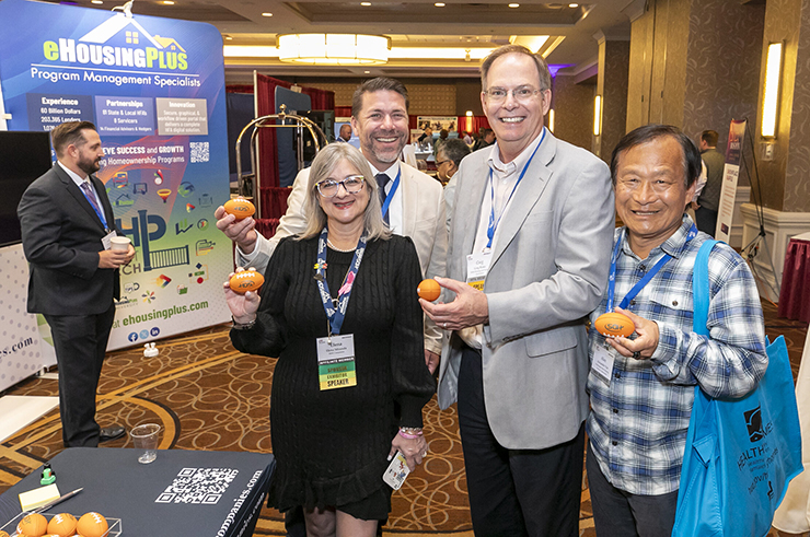 Four people in an exhibit hall, smiling